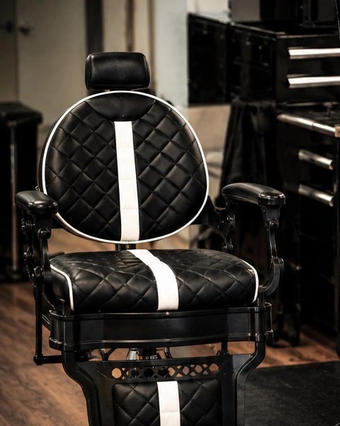 A Tactical Grooming barber chair in black diamond-stitched leather
