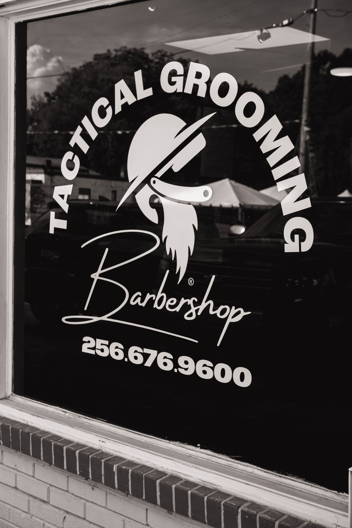 Tactical Grooming Barbershop storefront window with the shop logo and phone number